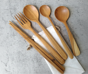Set of wooden cutlery including spoons and forks on a gray surface.